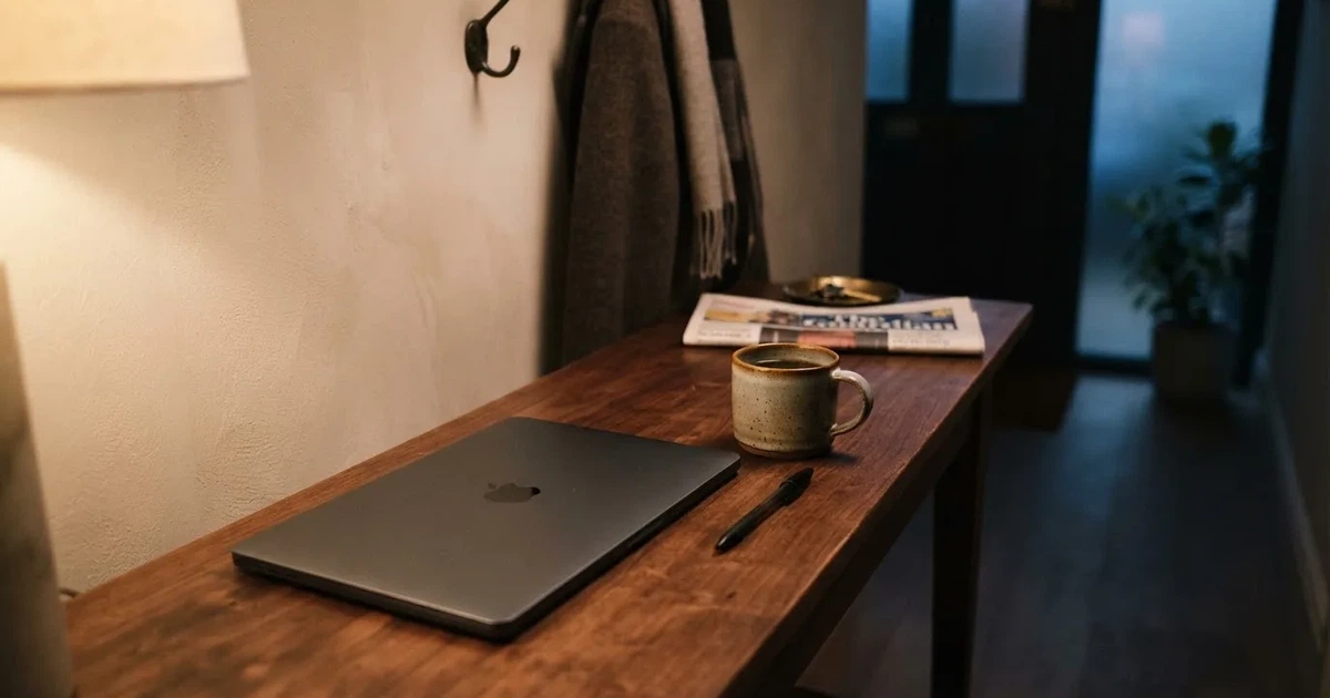 Kaffekopp och penna på ett smalt hallbord i skymning, en stängd bärbar dator vid sidan — 200 kr casino i sverige
